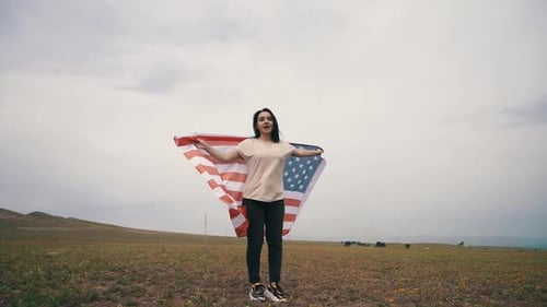 Woman Waving American Flag in Beautiful Grassy Field