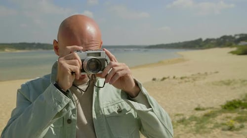 Man Holding Camera and Photographing on Beach