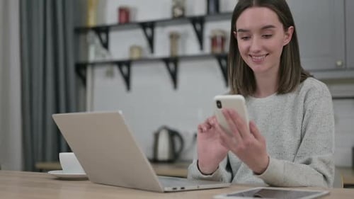 Smiling Woman Using Smartphone At Table
