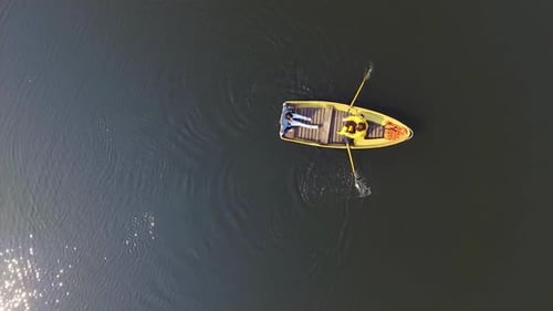 Two People in the Small Boat Boating Across a Beautiful Wide Reflective Lake or River