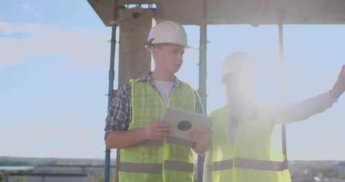 Construction Workers Discussing Building Plans on Tablet