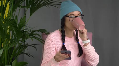 Mixed Race Hipster Woman Sitting in Cafe, Drinking Coffee and Using Smartphone