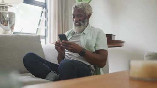 Mature Man Using Smartphone on Sofa