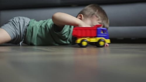 Young Child Plays with Toy Truck on Floor
