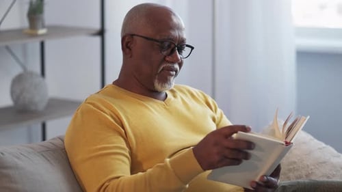 Senior Man Reads Book on the Couch
