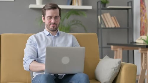 Man Works on Laptop While Sitting on Couch