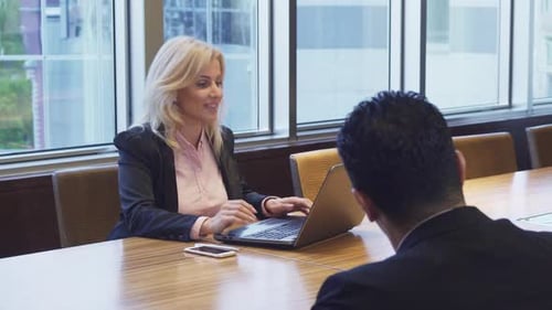 Woman Talks to Coworker and Types on Laptop