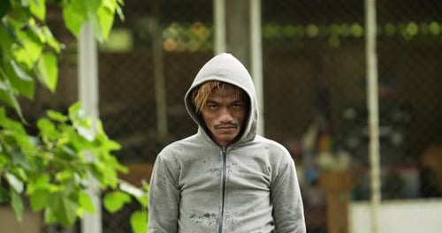 Homeless man holding help label and looking at camera.