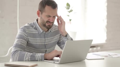 Man Working on Laptop Experiences Headache in Office