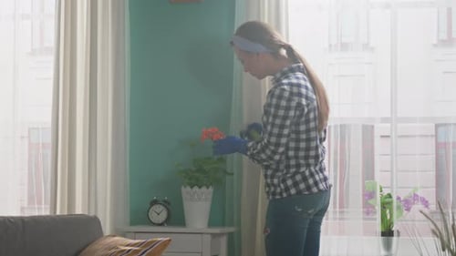 Woman Spraying Plant with Water Inside Home