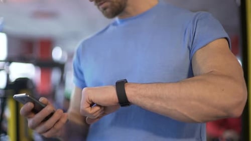 Man Using Smart Watch and Cellphone in Gym