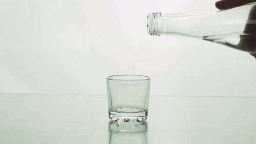 Pouring Liquid into Glass Cup on White Background