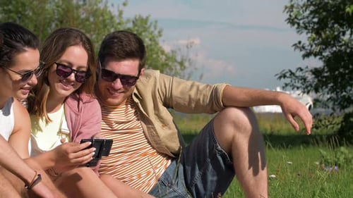 Friends Reviewing Pictures on Smartphone at Park