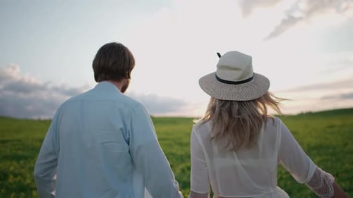 Countryside Cheerful Couple in Nature Man and a Woman are Running Through a Field of Rapeseed