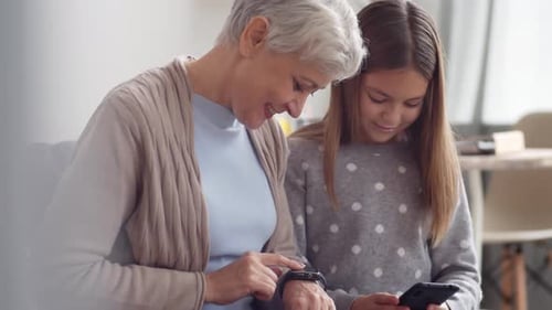 Grandmother and Granddaughter Using Technology Together Indoors