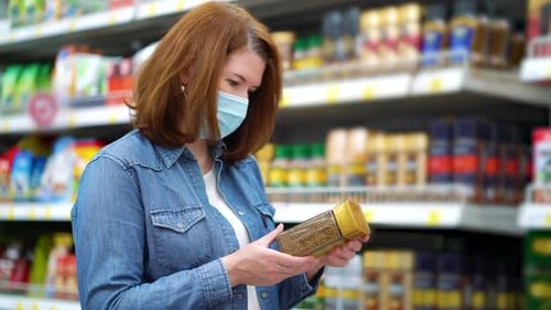 Young woman buying instant coffee in supermarket during COVID