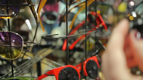 Venta de accesorios en grandes almacenes locales, cliente femenino que elige gafas de sol