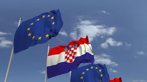 Croatian and European Union Flags Waving Against Blue Sky