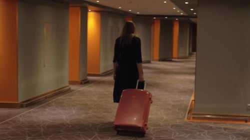 Woman with Suitcase Walking To the Room in Hotel Corridor