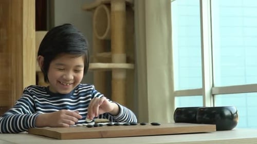Un joli garçon asiatique a appris à jouer au jeu de go chinois tout seul