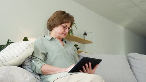 Woman Relaxing on Couch with Tablet