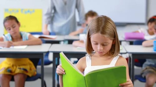 Child Reads in Classroom, Surrounded by Students