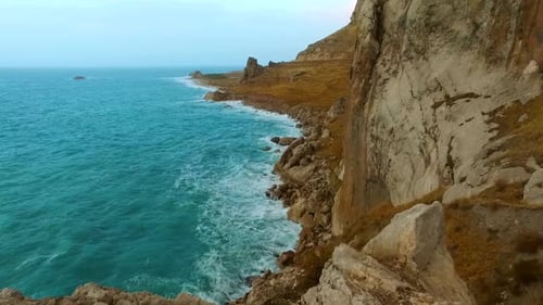 Waves crashing on high rocky cliffs on atlantic ocean at sunrise