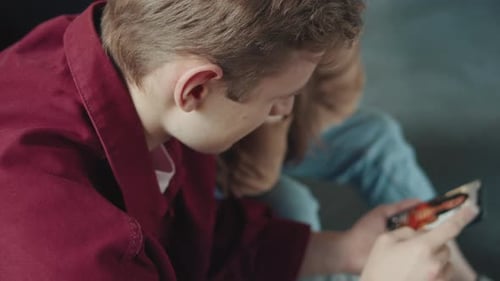 Young Teenage Couple Sitting in Campus or Office or University Using a Smartphone Applications