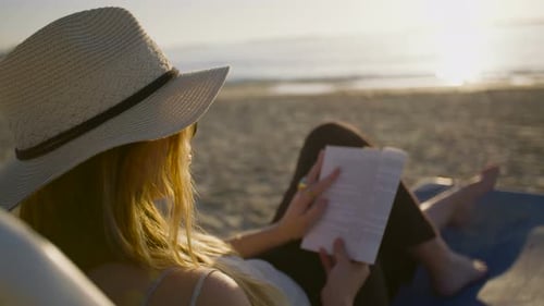 young attractive woman sitting on a beautiful beach reading a book
