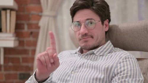 Man Sitting Indoors Says No With Finger