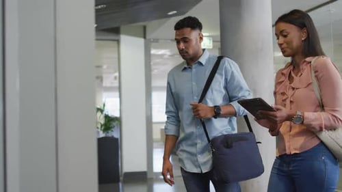 Man and Woman Talking While Walking in Office