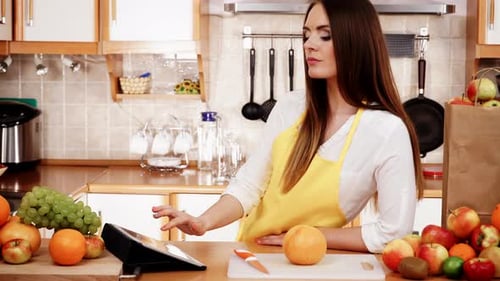 Woman Using Tablet with Fruit in Kitchen