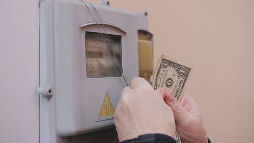 Mature Person Counting Dollars by Electric Meter