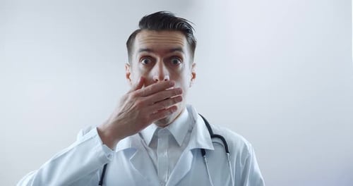 Surprised doctor covers open mouth with hand