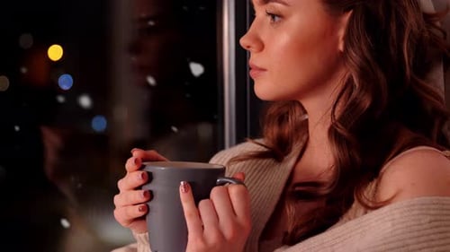 Woman with Coffee or Tea Cup on Windowsill at Home