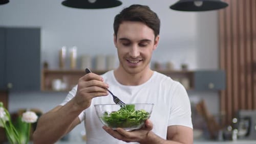 Young Man Enjoys Healthy Salad in Kitchen