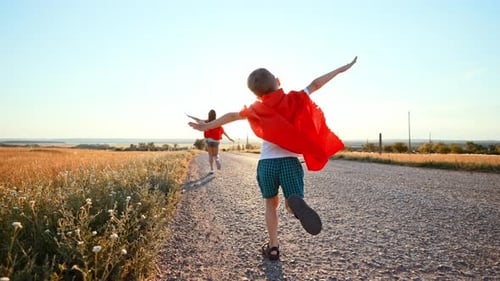 Two Running Children in Field Under Sunlight Brother and Sister Put Homemade Superheroes Costumes
