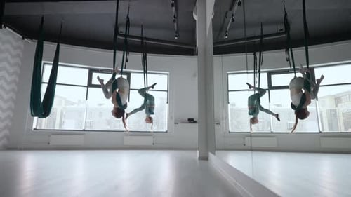 Women Performing Aerial Yoga Poses in Bright Studio
