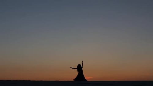 Silhouette of Woman Dancing at Sunset in Desert