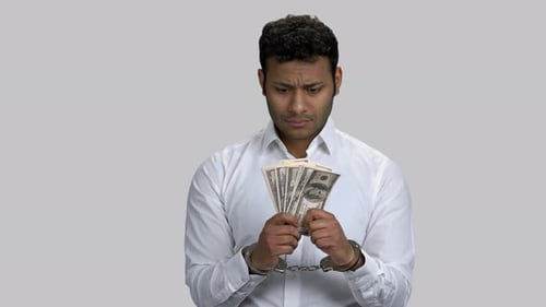 Man Handcuffed Looking at Stack of Cash