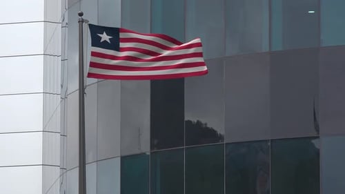 Animated Liberian Flag Waving on Flagpole Against a Modern Building