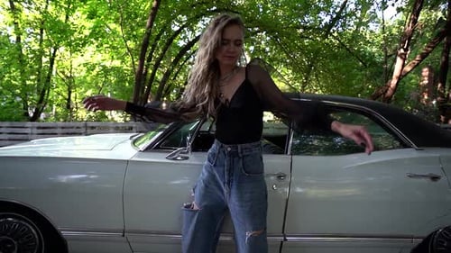 Blonde in Stylish Clothes Next To a White Classic American Car on the Street