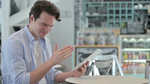 Creative Man Reacting to Loss on Tablet in Cafe
