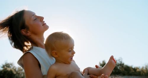 Beautiful Young Mom Holding Hands Spinning Little Happy Cute Son Playing Together at Nature