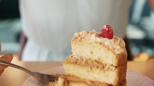 Woman Enjoys Delicious Cake with Raspberry Topping