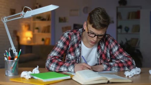 Stressed Teenager Writing at Desk at Night