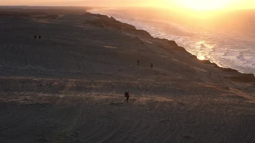 Hiker Walking Windblown Beach At Sunset