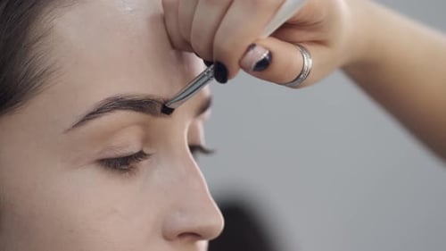 Detalhe do processo de desenhar as sobrancelhas do cliente no salão de beleza
