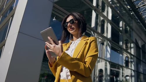 Woman Uses Tablet Outside Modern Office Building