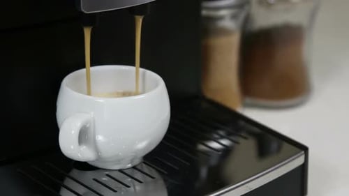 Coffee Machine Filling a White Cup with Coffee